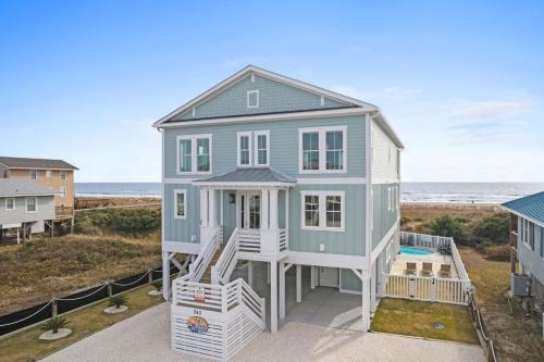 a house on the beach with the ocean in the background at Fish-N-Chips by the Sea home in Holden Beach