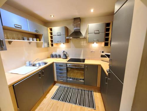 una pequeña cocina con fregadero y nevera. en Cosy Central Modern Apartment, en Nantwich