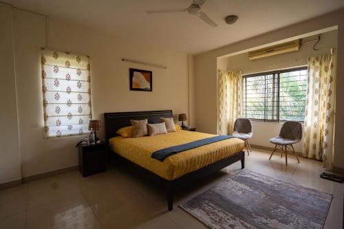 a bedroom with a bed and two chairs and a window at Luho 306 in Bangalore