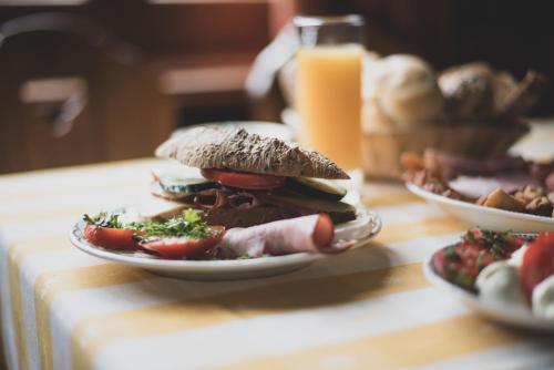 a sandwich on a plate on a table with a glass of orange juice at Öreg Prés Butikhotel in Mór