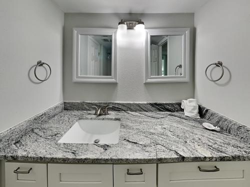La salle de bains est pourvue d'un lavabo et de deux miroirs. dans l'établissement Madeira Beach Yacht Club 247g, à St. Pete Beach