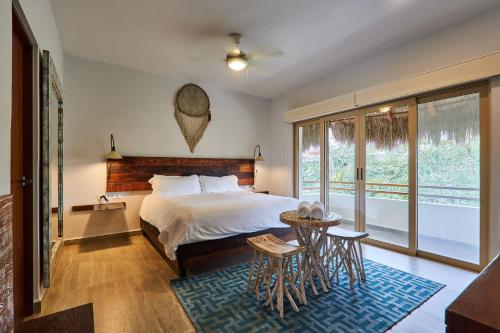 Schlafzimmer mit einem Bett, einem Tisch und einem Fenster in der Unterkunft Stunning Penthouse with Private Rooftop in Aldea Zama in Tulum