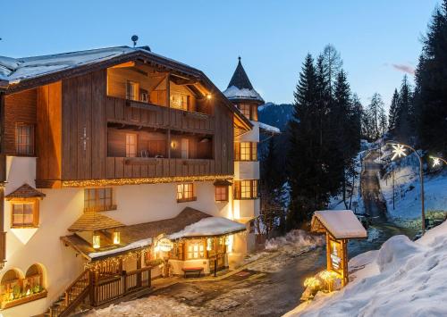 ein großes Gebäude im Schnee in der Nacht in der Unterkunft Bio Hotel Hermitage in Madonna di Campiglio