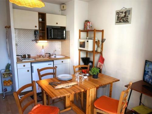 une petite cuisine avec une table et des chaises en bois dans l'établissement Charmant T2 RDC avec Jardinet et Parking, Proche Thermes et Commerces - FR-1-313-152, à Luchon