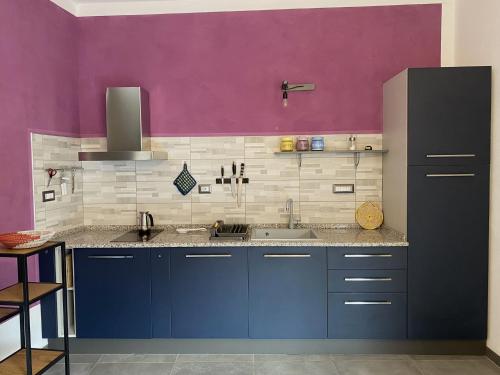 una cucina con armadi blu e parete viola di Gateway to Sinis a Baratili San Pietro
