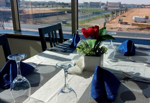 a table with wine glasses and a red flower on it at Address Sharurah Hotel in Sharurah