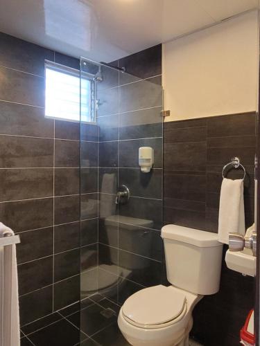 a bathroom with a toilet and a glass shower at Aparta Hotel Drake Piantini in Santo Domingo