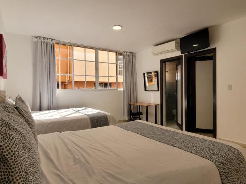 a hotel room with two beds and a window at Drake Piantini Santo Domingo in Santo Domingo