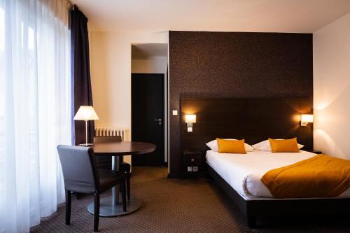 a hotel room with a bed and a table at Hotel Astrid Caen centre in Caen