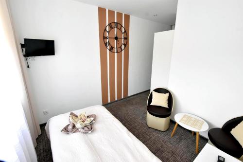 a room with a bed and a chair and a clock at Villa Sovita in Łeba