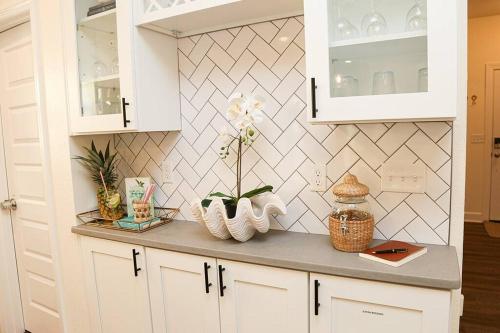 a kitchen counter with white cabinets and flowers on it at The Floridian Newly Built Dreamhome Central in Gainesville