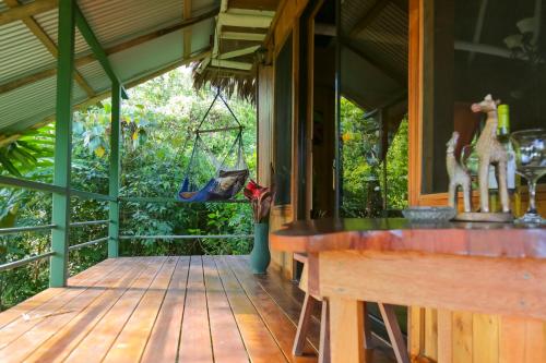 a porch of a house with a table and a swing at Casa Drake Lodge in Drake