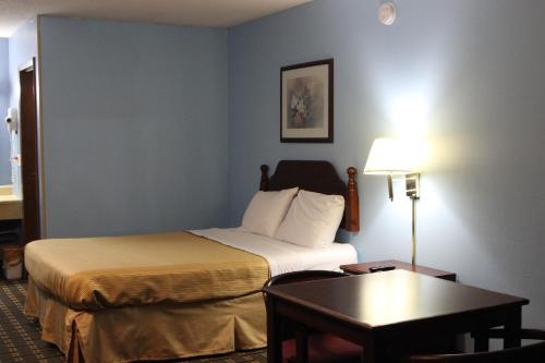 a hotel room with a bed and a table at Arcola Inn in Arcola