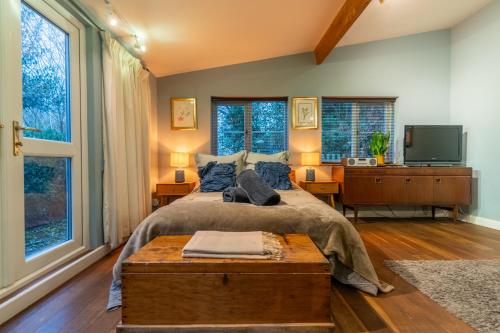 a bedroom with a bed and a tv and windows at Somerset Lodge, a secret hideaway in Bath