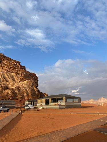 a building in the middle of a desert with a mountain at Magic nature camp in Wadi Rum