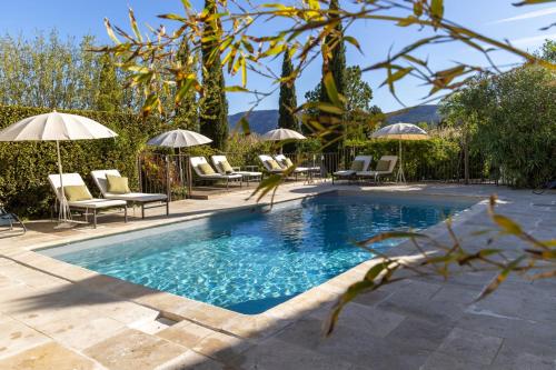 uma piscina com cadeiras e guarda-sóis em Le Clos de Lucie em Lagnes