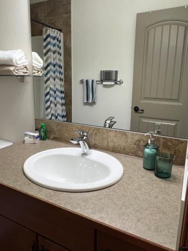 a bathroom counter with a sink and a mirror at Cochrane’s Finest Airbnb in Cochrane