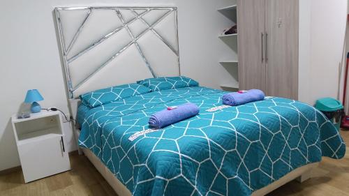 ein Schlafzimmer mit einem blauen Bett und lila Kissen in der Unterkunft Céntrico Departamento en el Prado in Cochabamba