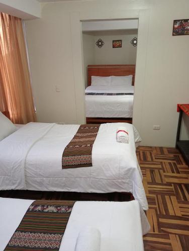 a hotel room with two beds with white sheets at Posada de Mama in Cusco