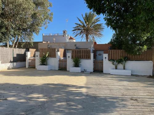 a house with a white fence and a gate at Estudios Eucalyptal El Palmar a 100 m del mar in El Palmar