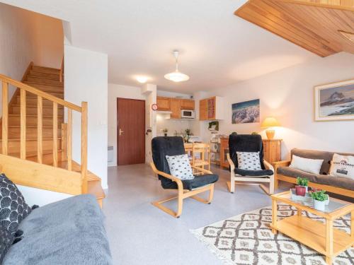 - un salon avec un canapé, des chaises et un escalier dans l'établissement Duplex confortable avec 2 chambres, balcon et parking à Saint Lary village, proche des thermes et télécabine - FR-1-296-336, à Saint-Lary-Soulan