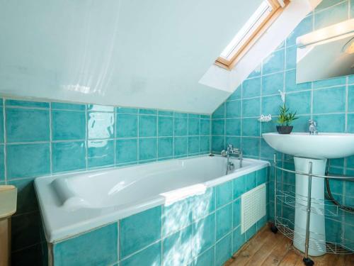 W wyłożonej niebieskimi kafelkami łazience znajduje się wanna i umywalka. w obiekcie Maison Vielle-Aure, 7 pièces, 11 personnes - FR-1-296-335 w mieście Vielle-Aure