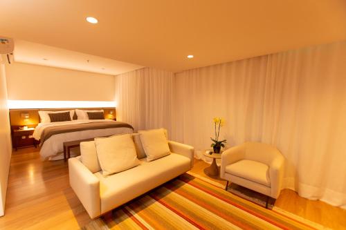 Quality Hotel Pampulha & Convention Center في بيلو هوريزونتي: غرفة نوم بسرير واريكة وكرسي