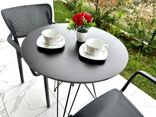 a black table with two cups and flowers on it at Shell Home golem 1 in Golem
