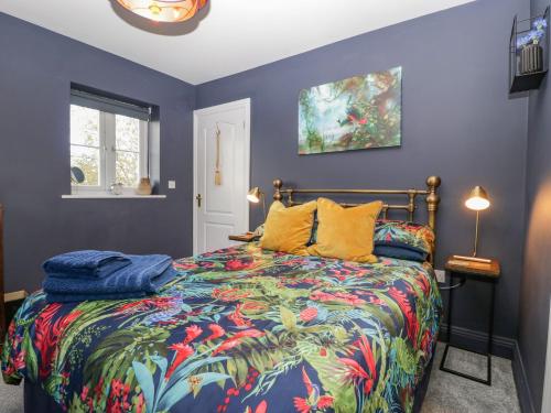 1 dormitorio con 1 cama colorida con almohadas amarillas en 8 Barrington Mews, en Ilminster