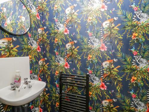 a bathroom with a blue wallpaper with birds on it at 8 Barrington Mews in Ilminster