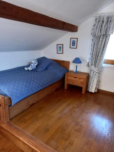 a bedroom with a blue bed and a wooden floor at le héron cendré in Lans-en-Vercors