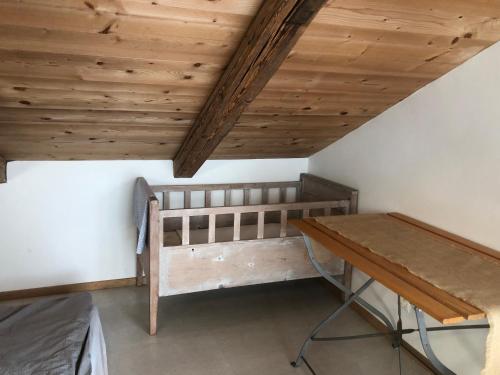 a room with a bed and a wooden ceiling at Sérénité et nature dans une ferme équestre - studio familial in Massonnens