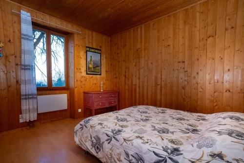 1 dormitorio con paredes de madera, 1 cama y ventana en La maison des Jolicoeurs, en Saint-Christophe-sur-Guiers