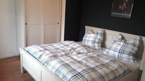 a bed with a plaid blanket and two pillows at Ferienwohung mit Blick auf die Pferdekoppel in Schotten