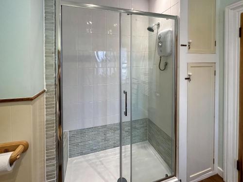 a shower with a glass door in a bathroom at The Headmasters Cottage in South Hill