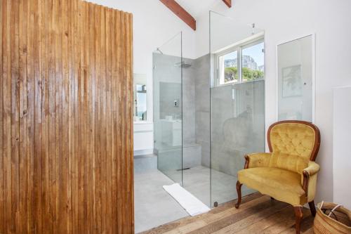 a bathroom with a shower and a yellow chair at Far Horizons Camps Bay in Cape Town