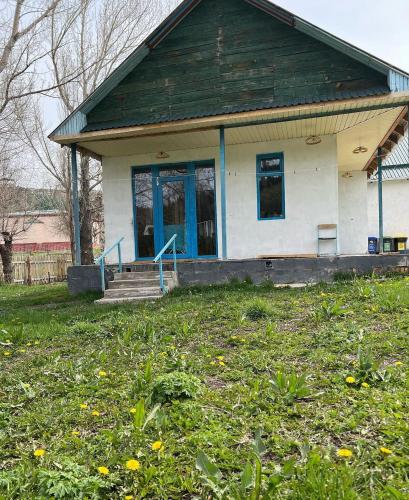 a small house with a blue door on a yard at Darya Hostel Jyrgalan in Dzhergalan