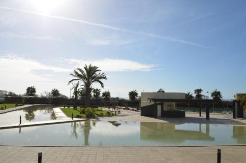 un edificio con una palmera frente a una piscina en Ocean Home EXCELLENT & SOLMARES, en Isla Canela