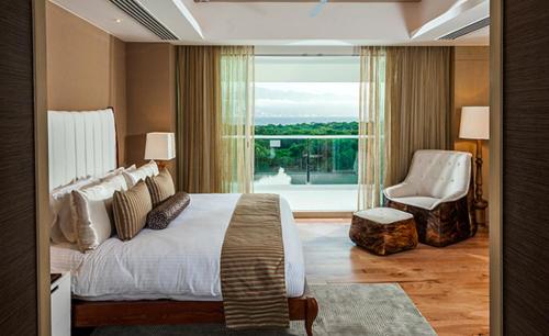 a bedroom with a bed and a chair and a window at Vidanta Grand Luxxe 3 BR Loft 16 rounds of Golf tennis 2 Massages included in Nuevo Vallarta