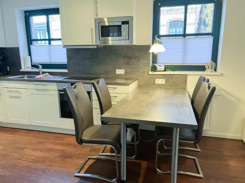 eine Küche mit einem Tisch, Stühlen und einer Mikrowelle in der Unterkunft "Windrose" in der Villa am Marienhof in Borkum