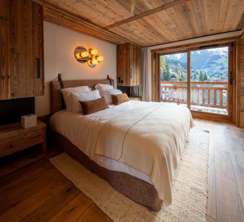 a bedroom with a large bed and a large window at Chalet Enigma in La Clusaz
