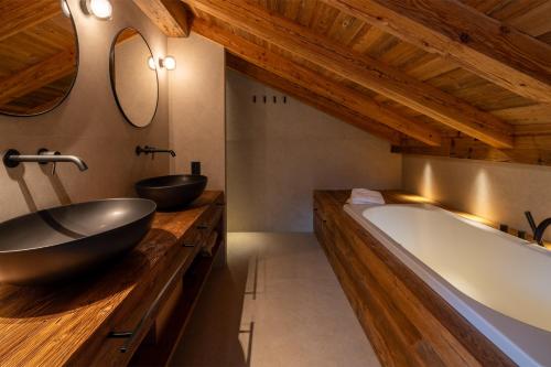 La salle de bains est pourvue de 2 lavabos et d'une grande baignoire. dans l'établissement Chalet Enigma, à La Clusaz