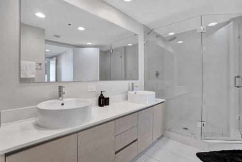 a white bathroom with two sinks and a shower at Gorgeous 4 Bedroom Condo Pool and Stunning Views in Hallandale Beach