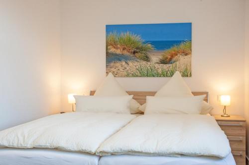 two white beds in a bedroom with a painting on the wall at "Kutje" in der Residenz zum Südstrand in Borkum