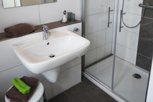 a white bathroom with a sink and a shower at "Kutje" in der Residenz zum Südstrand in Borkum