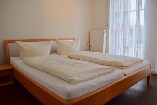 ein Bett mit weißer Bettwäsche und Kissen in einem Schlafzimmer in der Unterkunft "Lachmöwe" im Möwennest Greetsiel in Krummhörn
