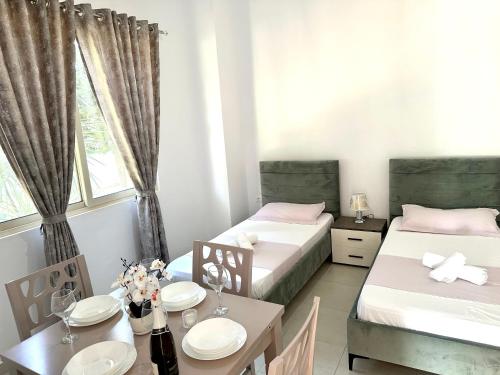 a room with two beds and a table and a dining room at Shell Home golem 1 in Golem