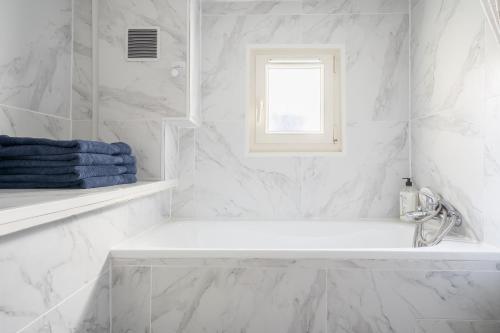 uma casa de banho branca com uma banheira e uma janela em Paris JO 2024 L élégante em Soisy-sous-Montmorency
