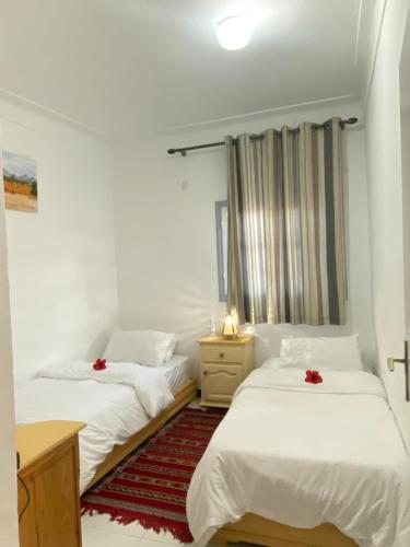 two beds in a room with white walls at Latifa house in Oualidia