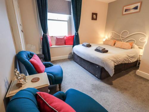 a bedroom with a bed and two chairs and a window at The Old Betting Shop in Keswick